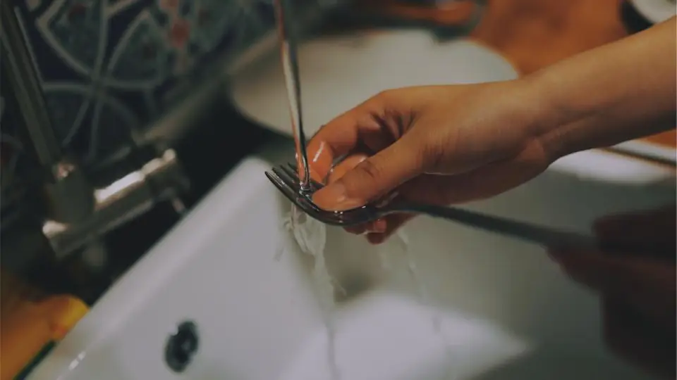 Metal implement being rinsed under a running tap